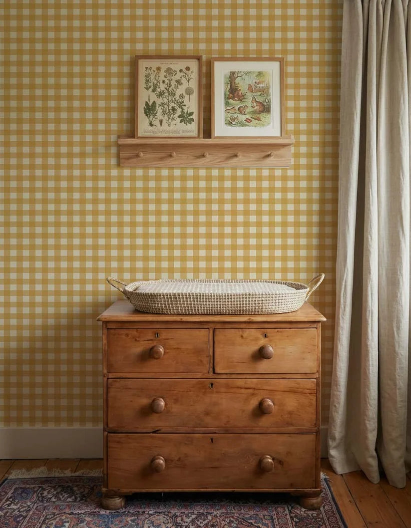 Ockergelbe Gingham-Tapete von Atelier Chien hinter einer Holzkommode mit Wickelkorb.